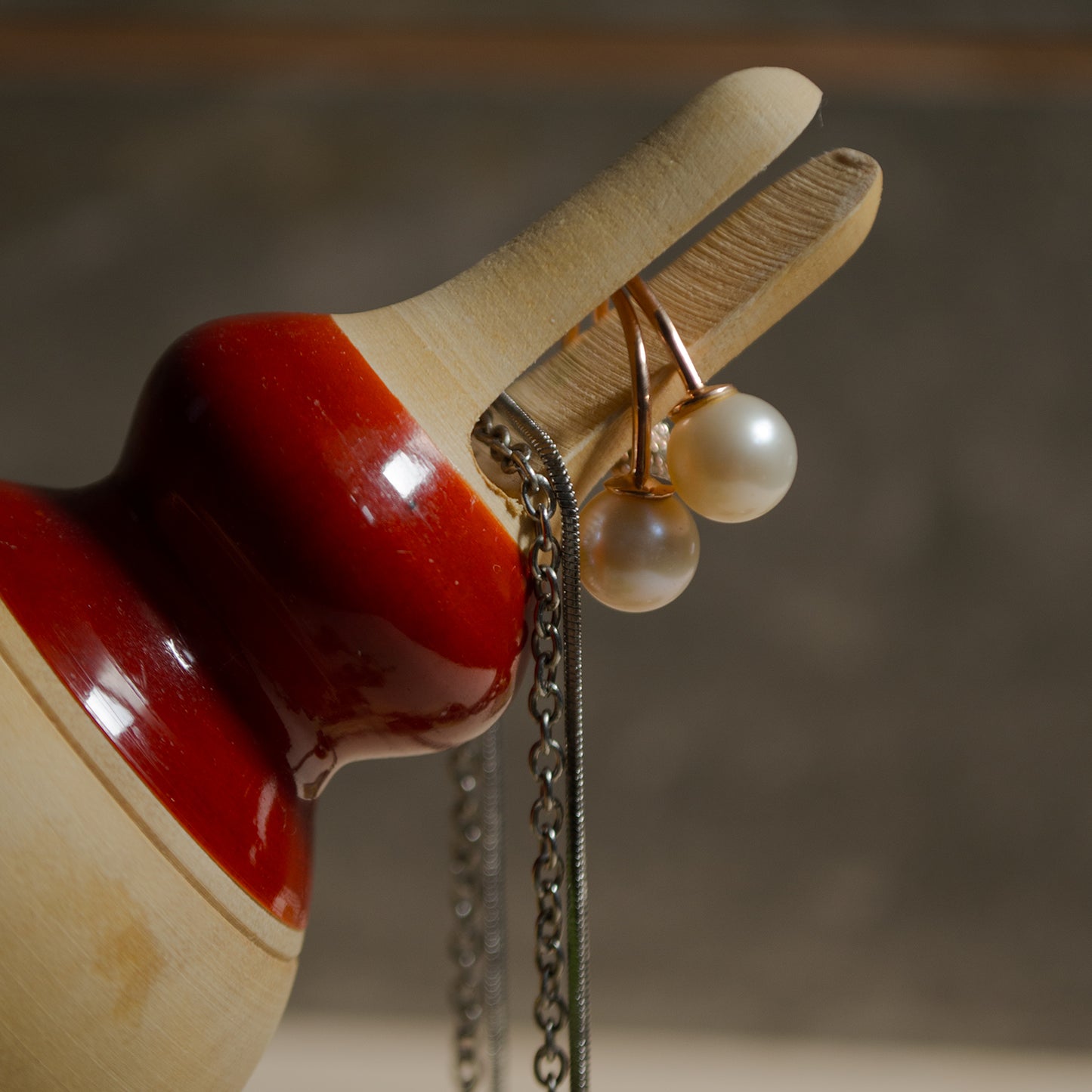Red wooden bird holding earings, handcrafted in channapatna.