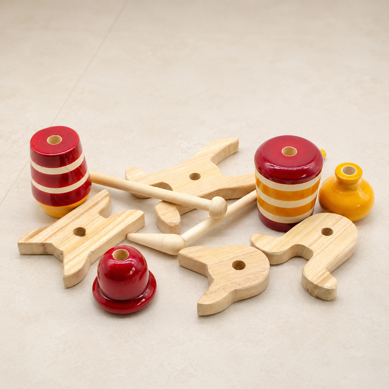Wooden toys with red and yellow striped cylindrical pieces on a beige surface