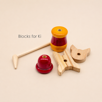 Set of wooden toys including a mallet, red and yellow top, and wooden block on a beige background.