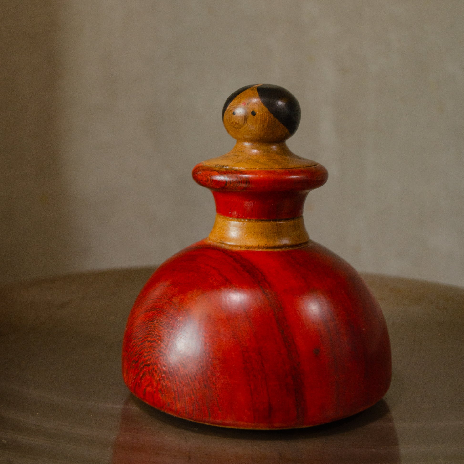 A wooden kitchen roaster with a red finish, resembling a character in design, placed on a flat surface. 