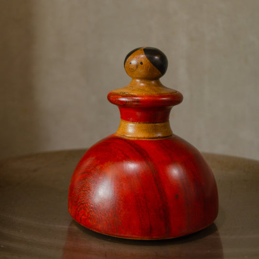 A wooden kitchen roaster with a red finish, resembling a character in design, placed on a flat surface. 