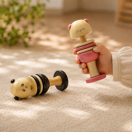 Hand playing with cat and panda inspired wooden toy rattle for baby, handcrafted in channapatna